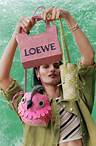 A female model holding up a trio of colourful LOEWE bags.