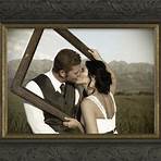Custom frame design with young couple kissing through an empty frame with mountains and fields in the background.